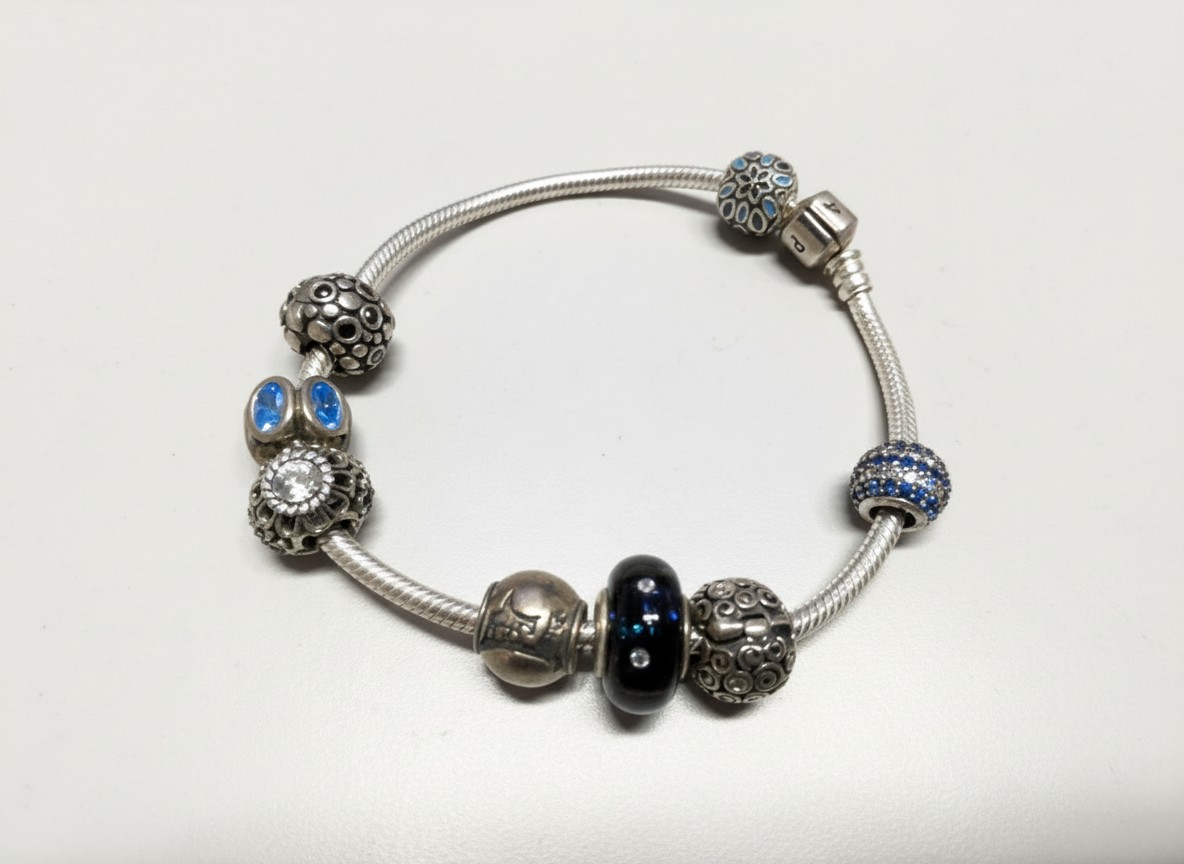 Pandora Moments Armband mit Charms, Silbernes Schlangenarmband mit verschiedenen Charms, darunter blaue und verzierte Elemente. | Zustand: Gebraucht | Farbe: silber
