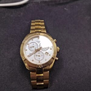 Tissot PR 100 Chronograph Gold, Damenuhr mit goldfarbenem Gehäuse, weißem Perlmutt-Zifferblatt und Chronographenfunktion. | Zustand: Gut