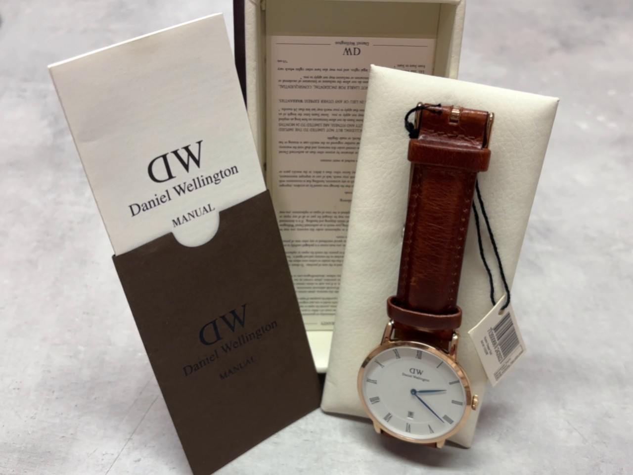 Daniel Wellington Dapper 38mm Roségold, Herrenuhr mit weißem Zifferblatt, Datumsanzeige, blauen Zeigern und braunem Lederarmband. | Zustand: Neu | Farbe: Gold | Braun