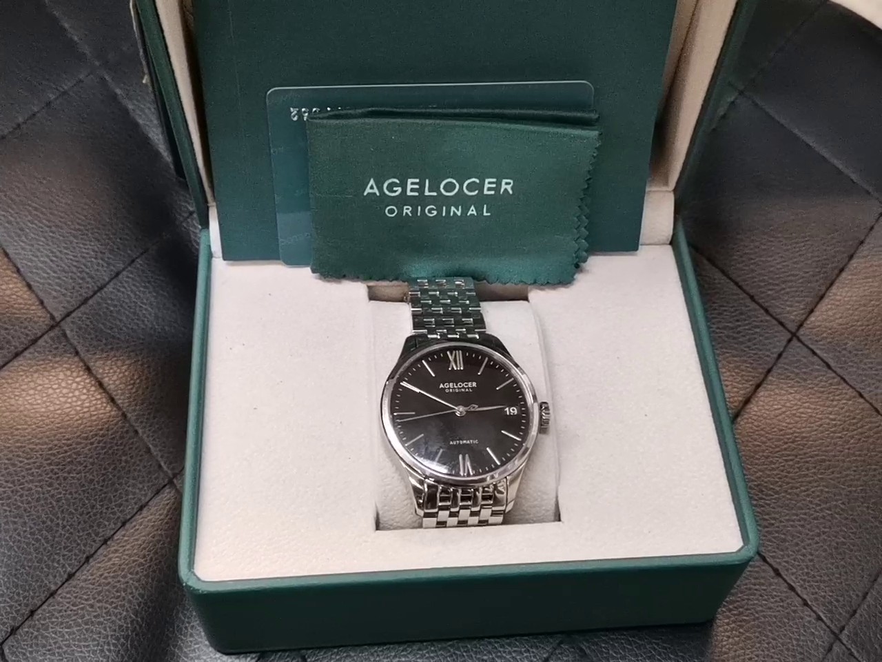 Agelocer Budapest Automatic Stahl Schwarz, Elegante Automatikuhr mit EdelstahLadegerätehäuse und -armband, schwarzem Zifferblatt, römischen Ziffern, Datumsanzeige sowie originaler Box und Zubehör | Zustand: Sehr Gut