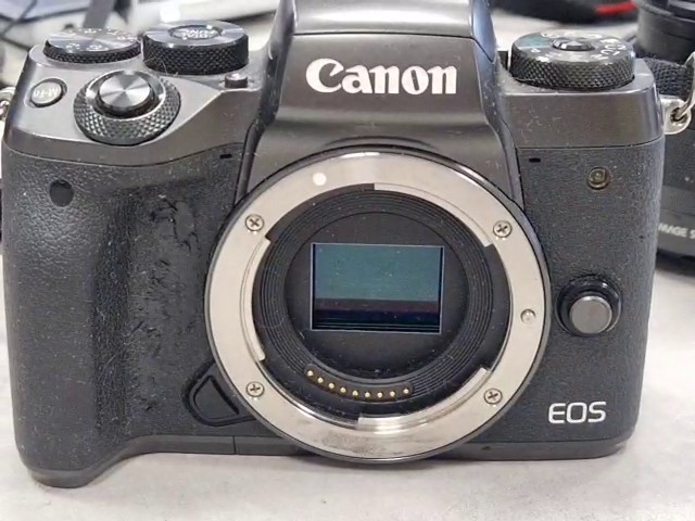 Canon EOS M5 2016 Schwarz, Spiegellose Systemkamera, 24,2 Megapixel, APS-C Sensor, abgenutzter Gummigriff, stark verschmutzt, Zubehör: Trageriemen, 2x Akkus, Ladestation | Zustand: In Ordnung