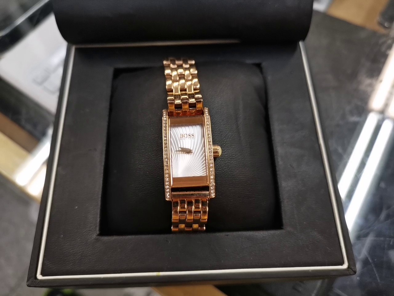 Hugo Boss Damenuhr Rosegold, Elegante Damen-Armbanduhr im rechteckigen Design mit funkelndem Kristallbesatz auf der Lünette, strukturiertem Zifferblatt und hochwertigem Gliederarmband in edlem Roségold, original verpackt | Zustand: Gut